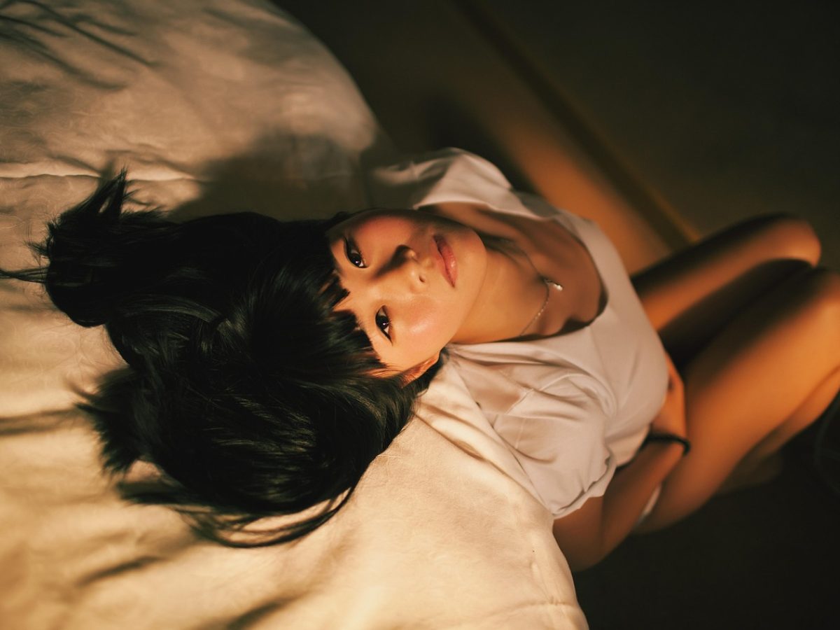 年轻女性在通勤地铁上低头看手机屏幕，车厢玻璃映出城市灯光，她正在查询科室挂号信息